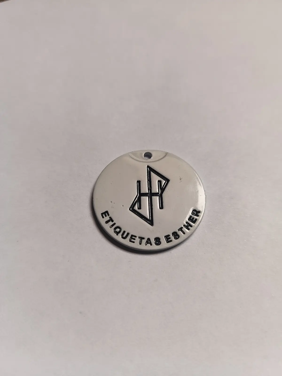 Medalla redonda de zamak en blanco, con monograma en relieve