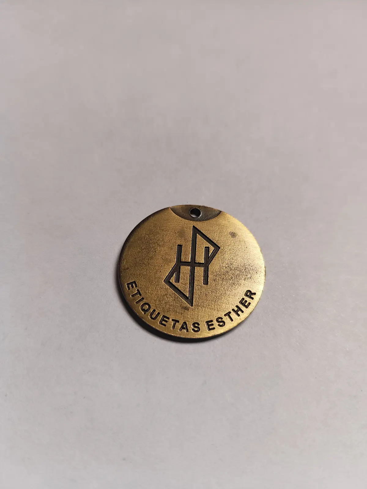 Medalla redonda de zamak en bronce tamboreado con un monograma en relieve
