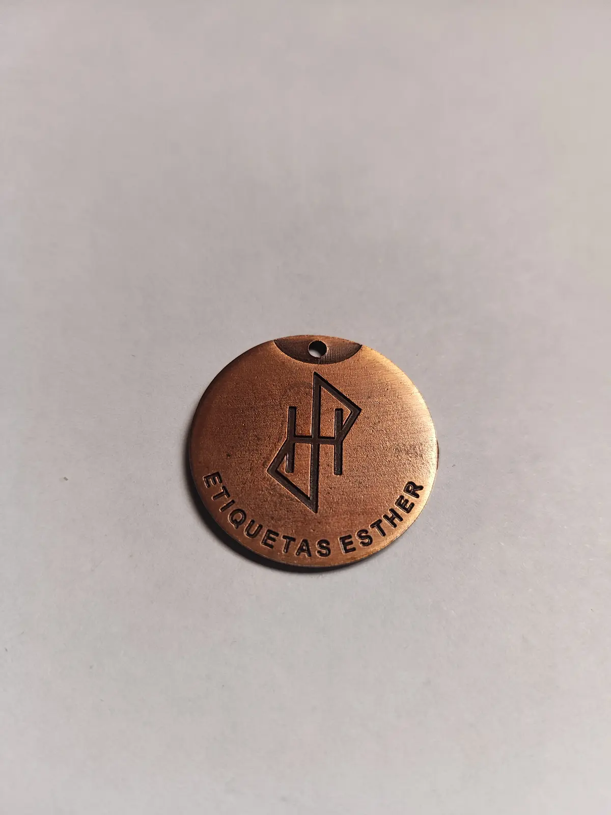 Medalla redonda de zamak en cobre brillante con monograma en relieve