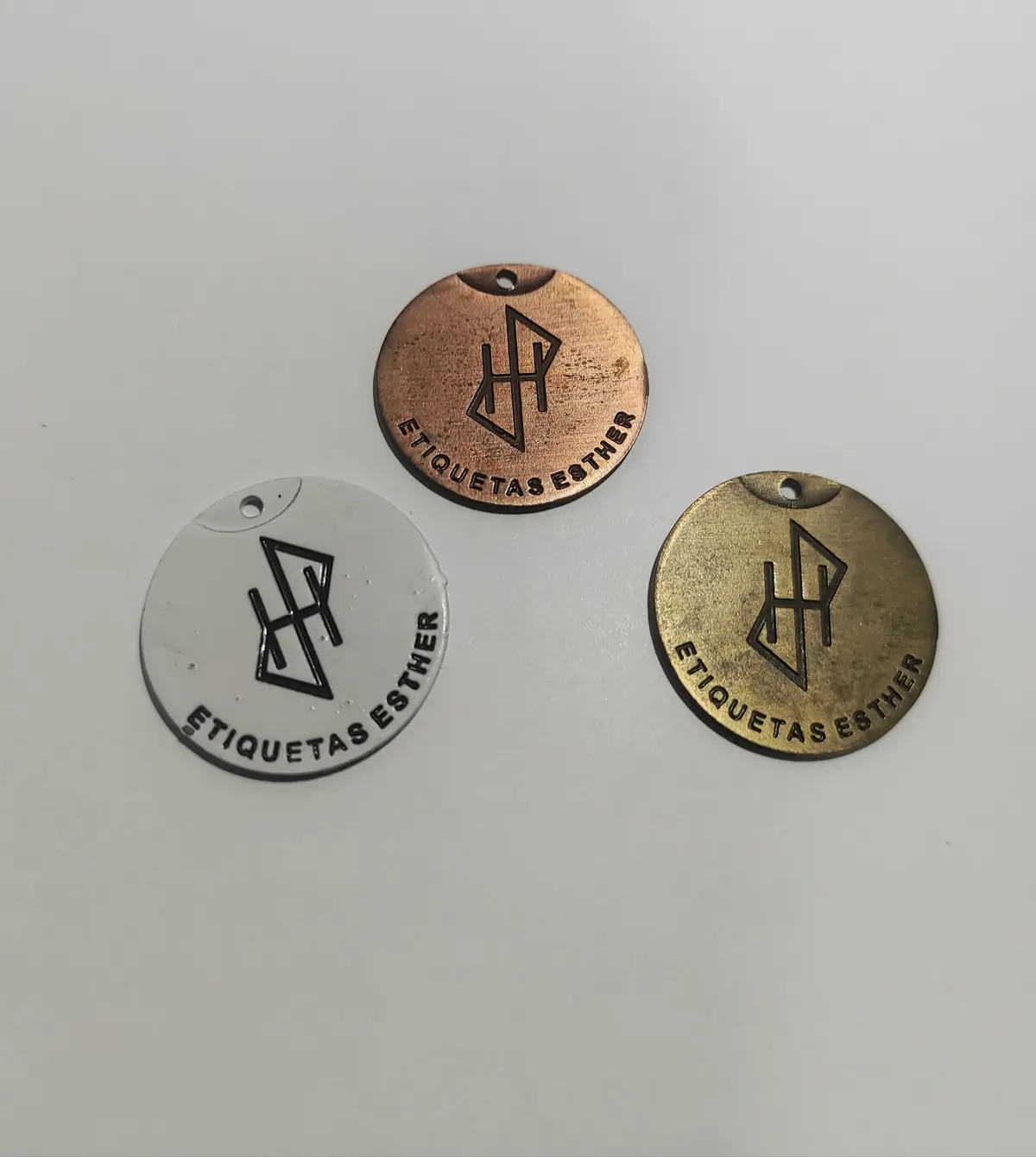 Tres medallas redondas de zamak juntas, en cobre, blanco y bronce tamboreado