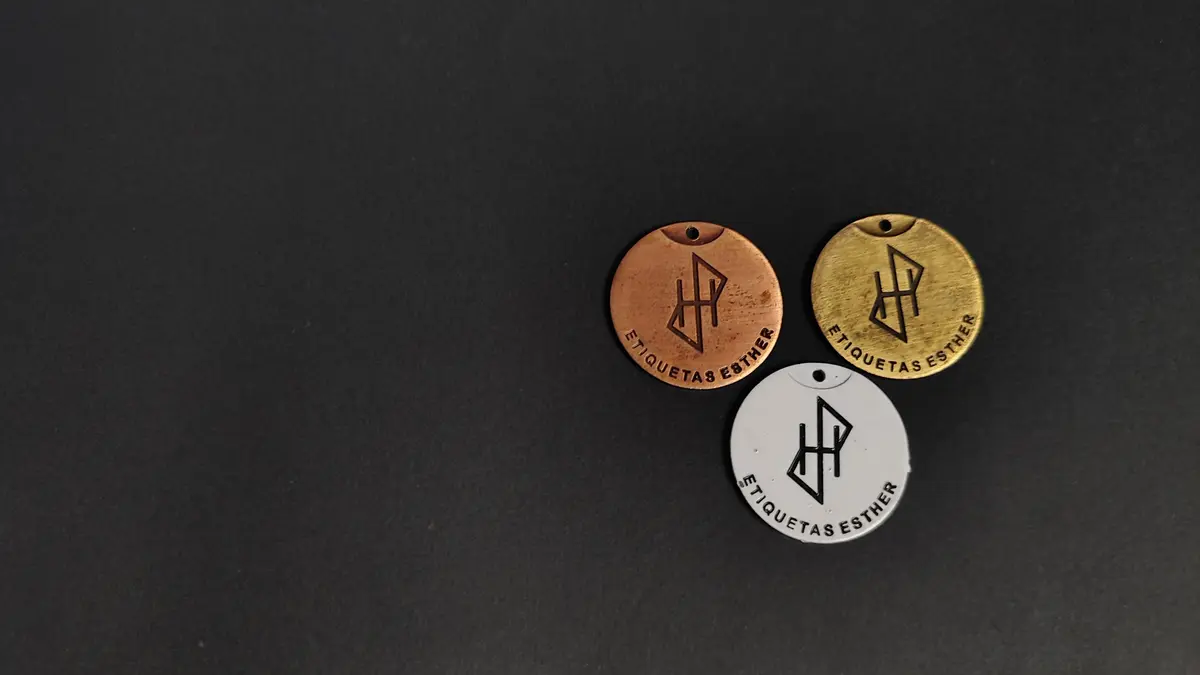 Tres medallas redondas de zamak en cobre, blanco y bronce tamboreado sobre fondo oscuro