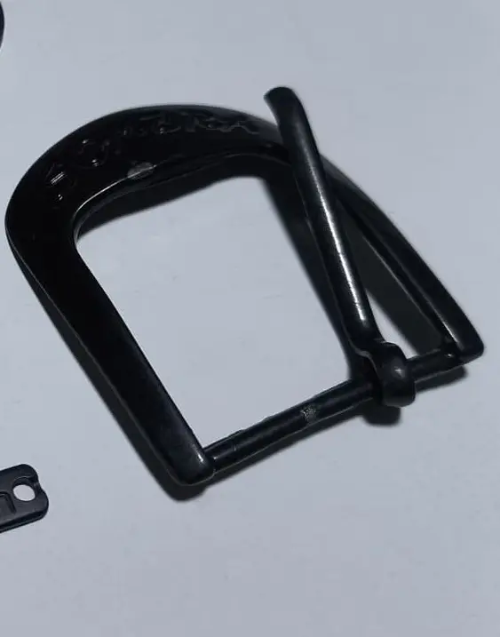 Hebilla de zamak en acabado negro mate, con la marca grabada en el arco
