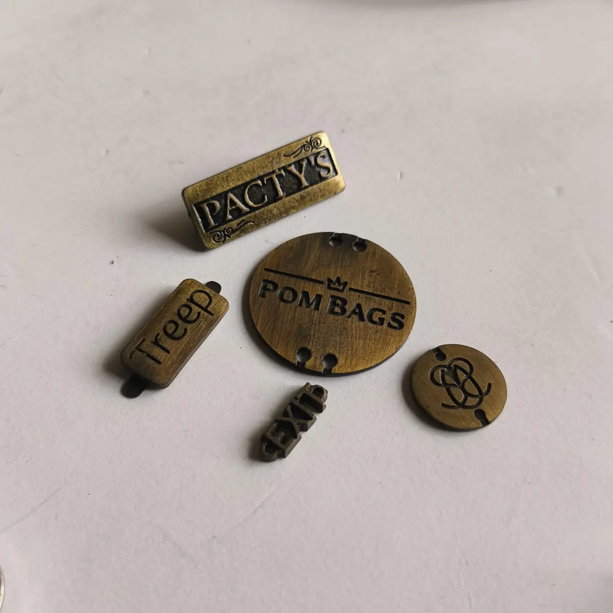 Surtido de placas y etiquetas metálicas en bronce tamboreado, de varias formas y tamaños