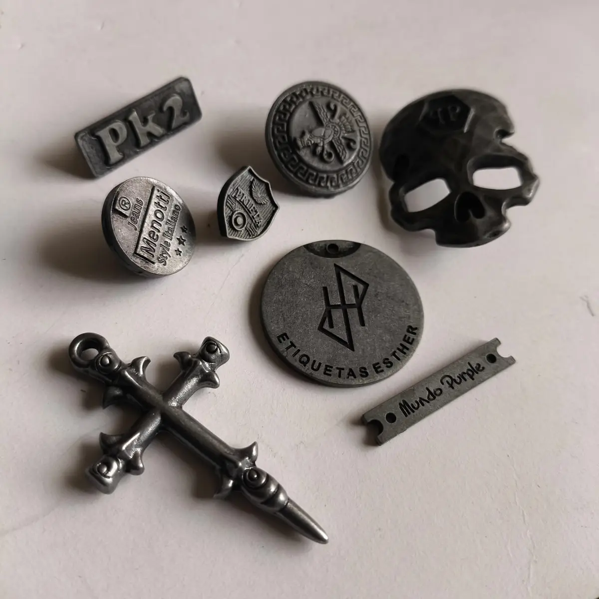 Surtido de piezas de zamak en gris pistola, con formas figurativas y placas grabadas