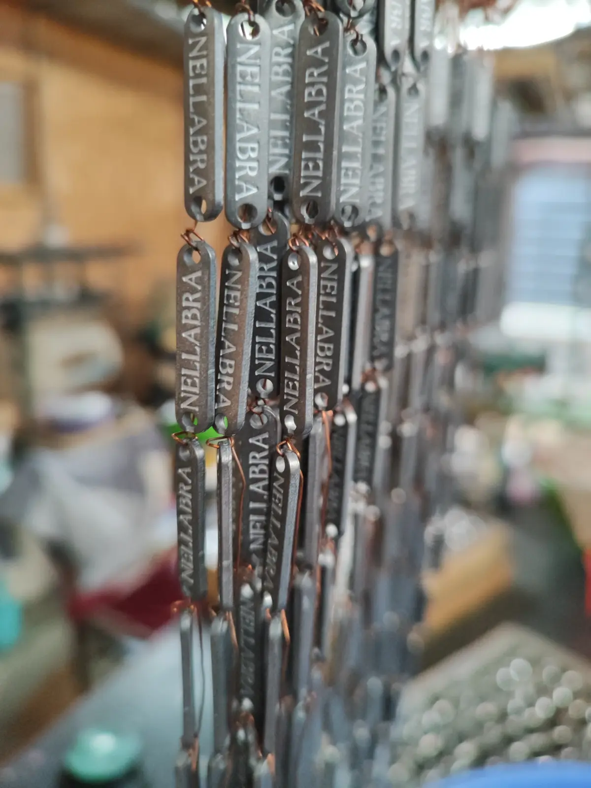 Etiquetas metálicas colgadas en hileras de alambre de cobre, en el bastidor del baño de electroplating